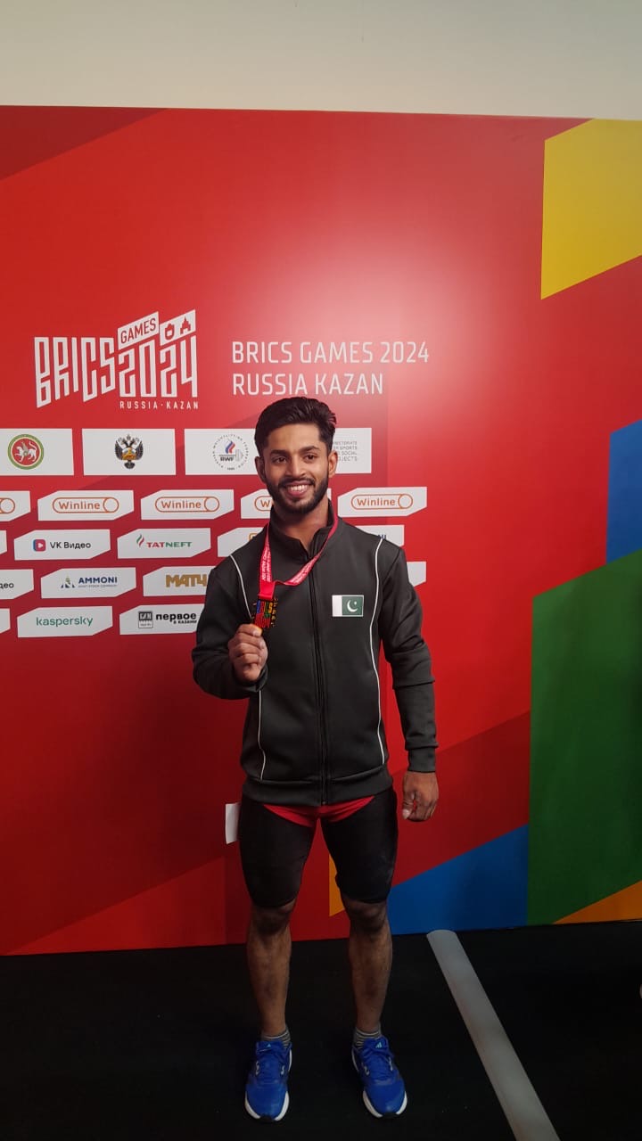 Haidar Sultan of Pakistan wins First Gold Medal while Daniyal Aftab secures 4th Position in the Weightlifting event of BRICS Games being held at Kazan city of Rusia. In the third day of the BRICS Games, Daniyal Aftab of Pakistan secured 4th position in the 89 kg body weight category. Daniyal Aftab participated in the 89 kg body weight category and lifted 133 kg in the Snatch and 165 kg in the Clean & Jerk events, with a total lift of 298 Kg, which was 4 kg more than his best total at any domestic competetion. This was first appreance of Daniyal Aftab at any international event. Earlier, in a stunning competition with Russians, Haider Sultan of Pakistan had won the first ever Gold Medal for Pakistan in BRICS Games, being held in the Kazan city of Russia. Haidar Sultan contested in the 61 kg body weight category and lifted a total weight of 261 Kg i.e. 115 kg in Snatch and 146 kg in the Clean & Jerk. It was his outstanding performance at any national or international competition. Haider Sultan was far behind his Russian competitors in the Snatch event; but his final stunning and courageous lift of 146 kg in the clean & jerk event turned conclusive, for his maiden victory at the international BRICS Games, on 13th June 2024. Haidar Sultan hails from Gujranwala district of Punjab and represents Pakistan Army at the National level. The team was accomponied by the seasoned and professional coach Mr. Shuja Ud Din Malik, who himself had been the Commonwealth Games 2006 Gold Medalist and Record holder. The motivation by Mr Imdaullah Meman, the chef-de-mission, and the technical expertise of the coach Mr Shuja ud Din Malik, maintained fighting spirit of Haidar Sultan and Diniyal Aftab. The Interim Committee of Pakistan Weightlifting Federation (PWLF) with the financial and administrative support of the PSB had fielded a two members weightlifting team in the BRICS Games, despite tough resistance and blackmailing by the ex-officials of the PWLF, which has been suspended by the PSB due its involvement in systemetic doping, financial corruption, gross mal-administration, nepotism and violation of merit. Haidar Sultan along with other top players was deprived of his participation in the 2023 Asian Games Hangzue, despite being on merit and recommendations by the Interim Committee. Haidar Sultan was excited on his victory and thanked PSB and the Interim Committee of PWLF for their support and his selection on merit. He expressed his commitment to continue training for the Asian, Commonwealth and World Championships. Stunning victory of Haidar Sultan has brought a ray of hope in the gloomy field of sports, where cricket has disappointed the entire nation. The Pakistan Times 